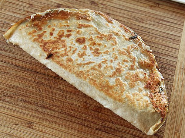 A golden brown ramp quesadilla on a cutting board.