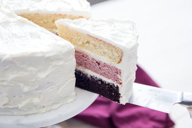 A slice of Neopolitan cake being cut from the cake. 
