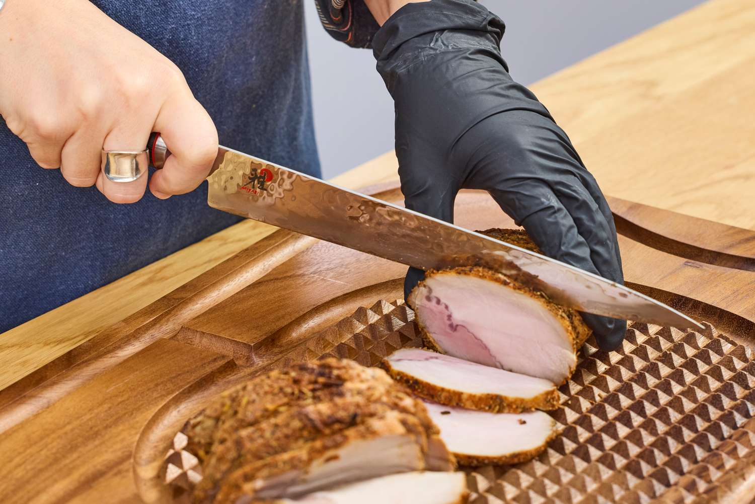 A person slices meat with the Miyabi Mizu SG2 9.5 Inch Slicing Knife