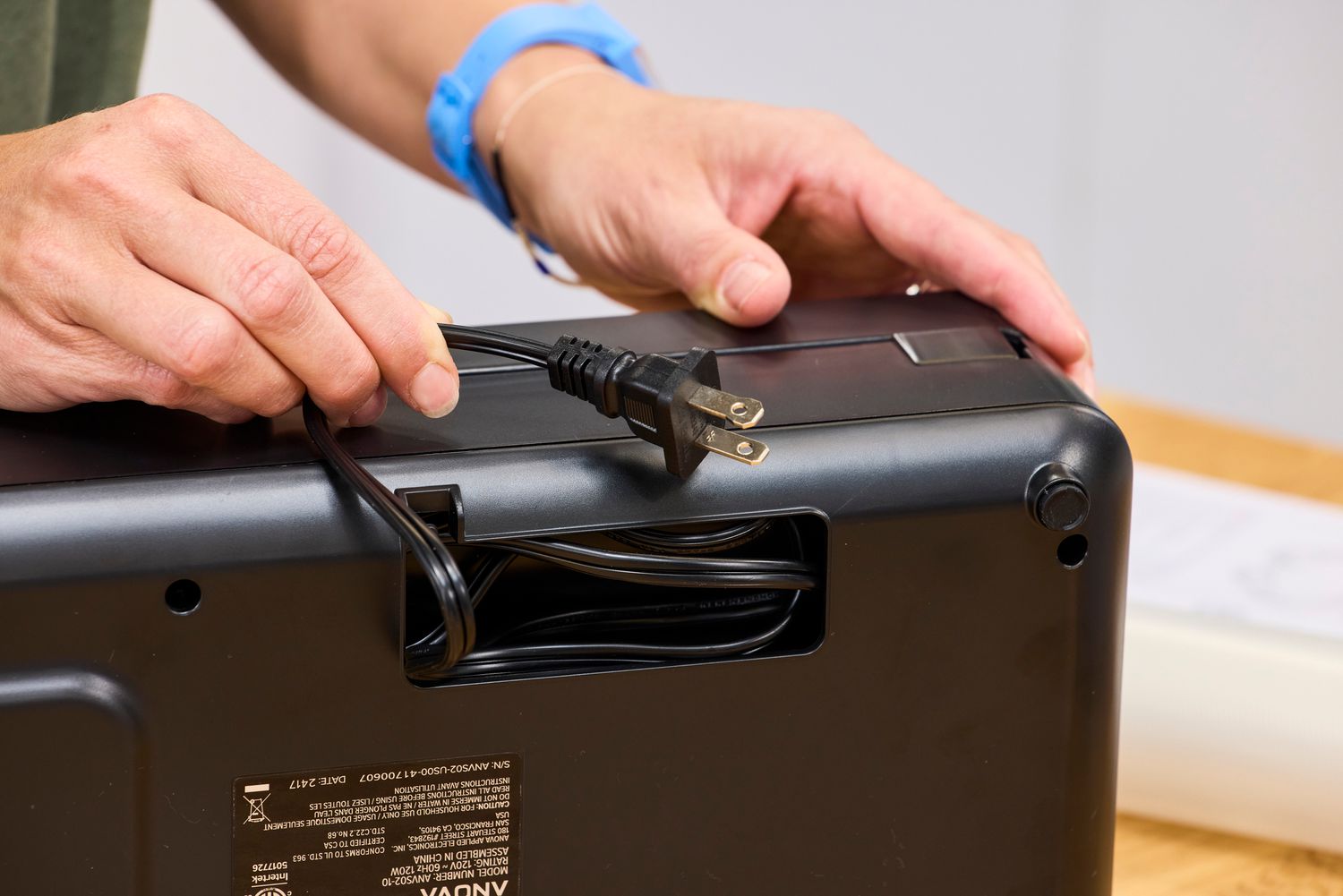 A person unwinds the power cord on the Anova Precision Vacuum Sealer Pro