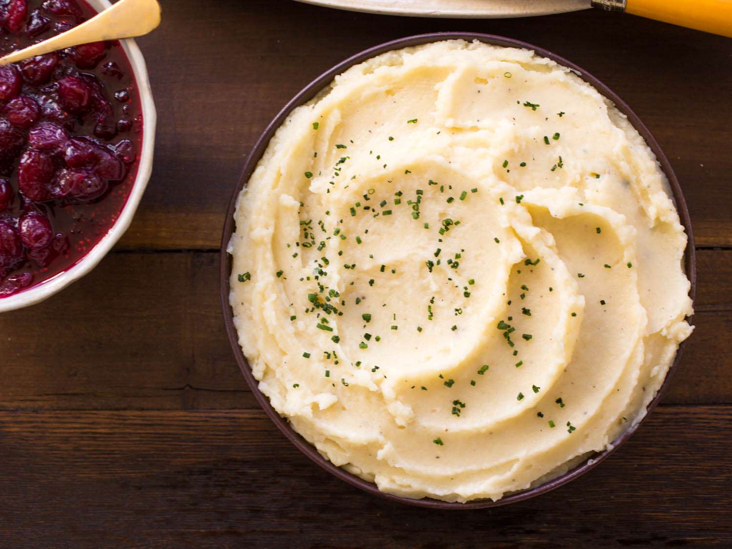 Overhead shot of a bowl of mashed potatoes and a dish of cranberry sauce