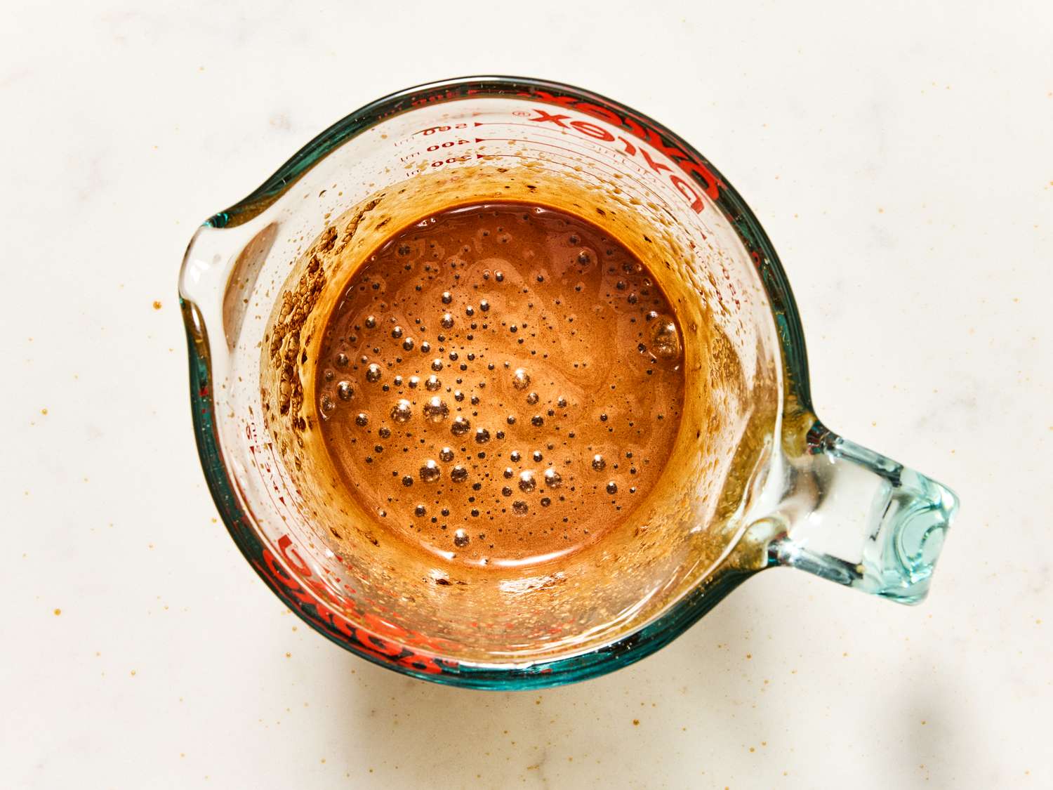 A measuring cup containing frothy coffee mixture viewed from above