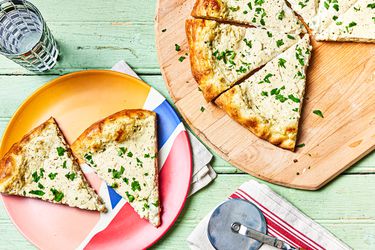 Overhead view of a sliced NY style white pizza with two slices on an individual plate