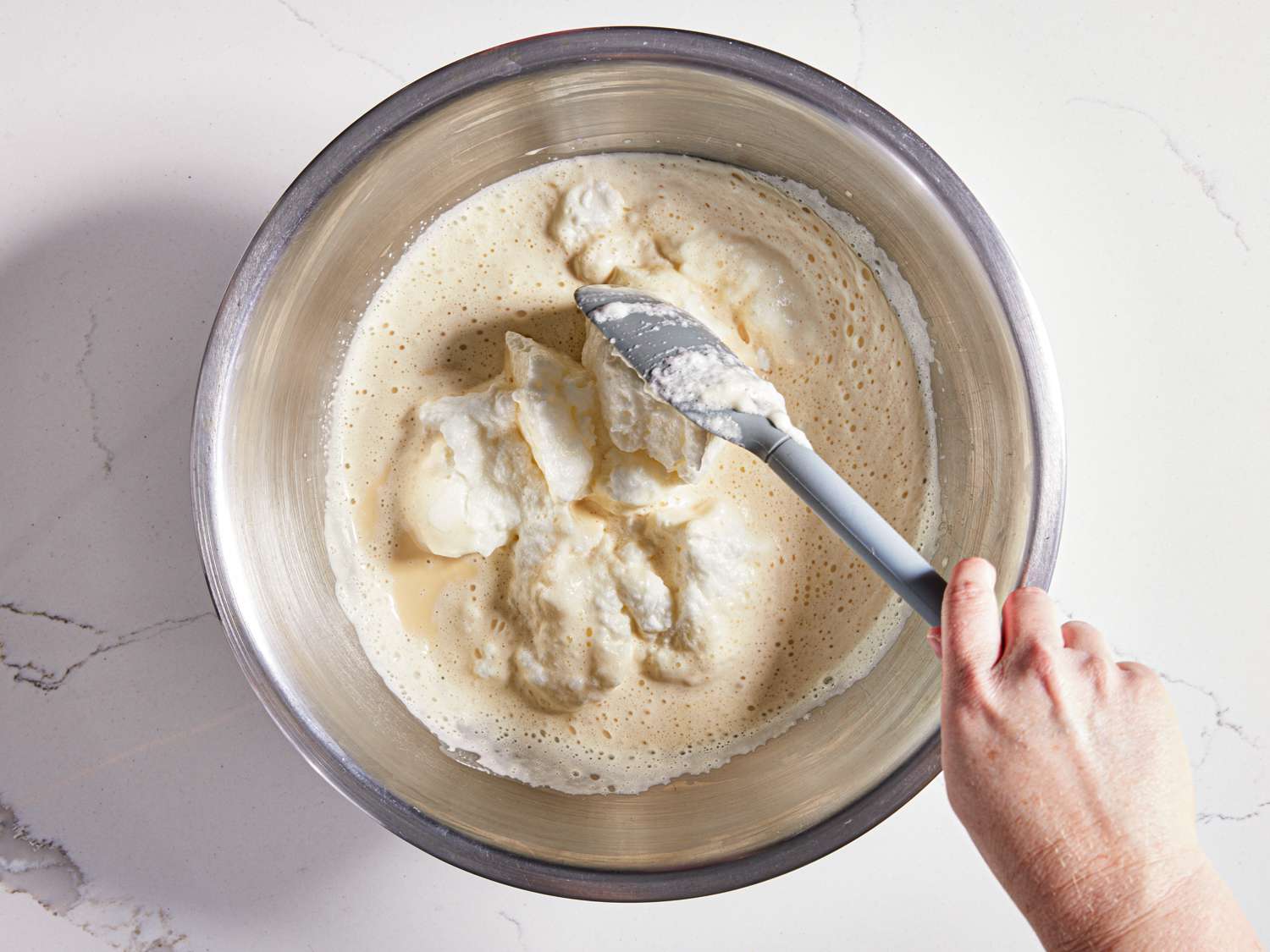 Egg whites being folded into yolk mixture with a rubber spatula 