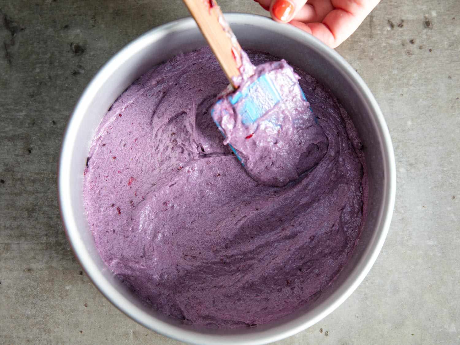 Spreading blackberry cake batter into a cake pan with a flexible spatula