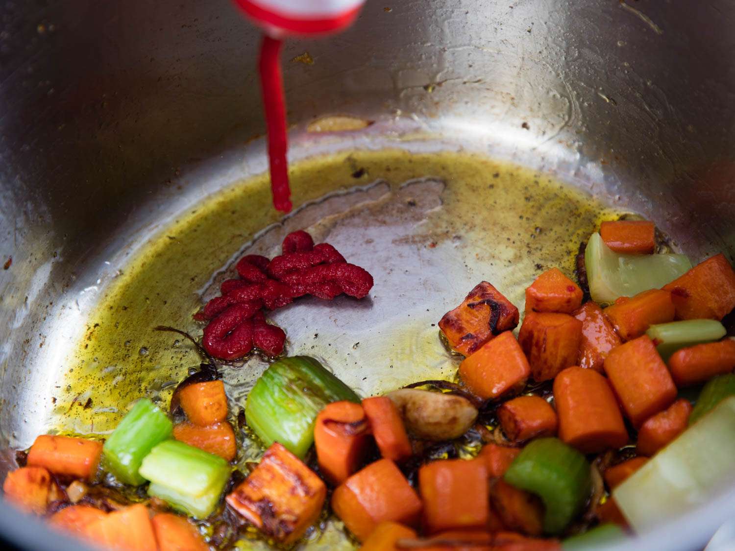 Adding tomato paste to browned vegetables in stockpot