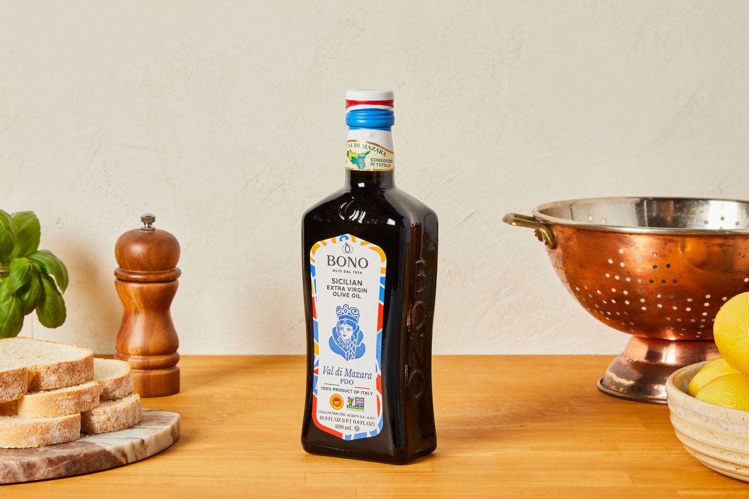 Bono Sicilian extra virgin olive oil bottle displayed on a wooden surface with surrounding kitchen items