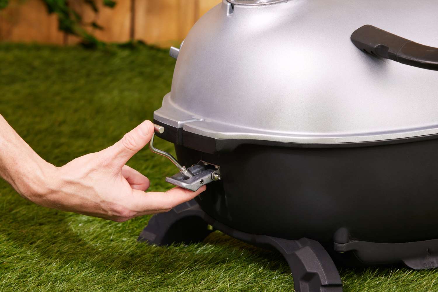 A person clipping the PK Grills grill closed.