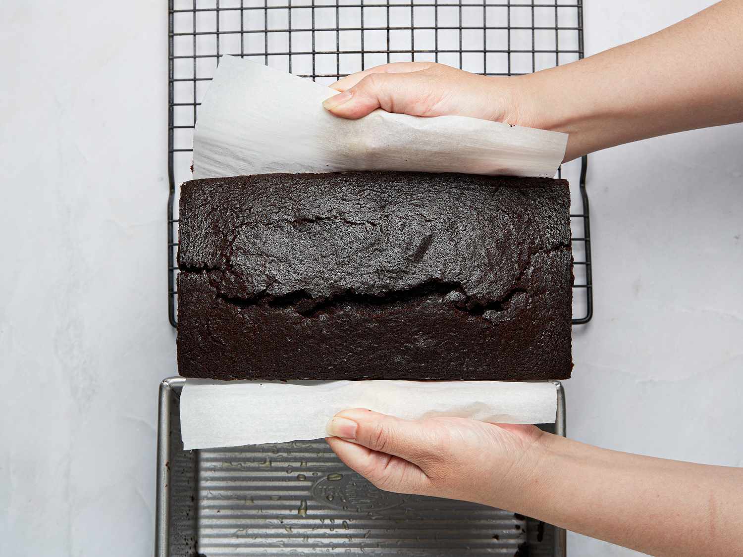 pulling parchment paper with cake out of cakepan 