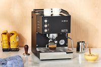 The Diletta Mio Espresso Machine brewing an espresso into a glass on a marble countertop