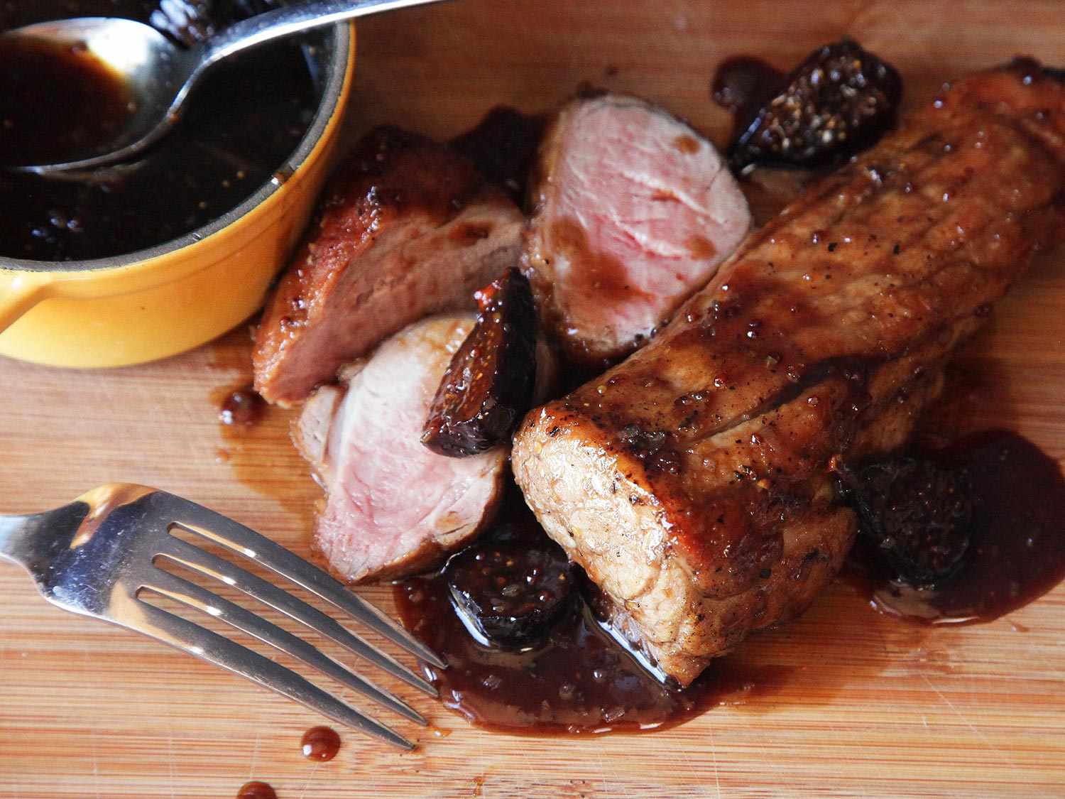 Sliced pan-roasted pork tenderloin next to a bowl of bourbon fig glaze.