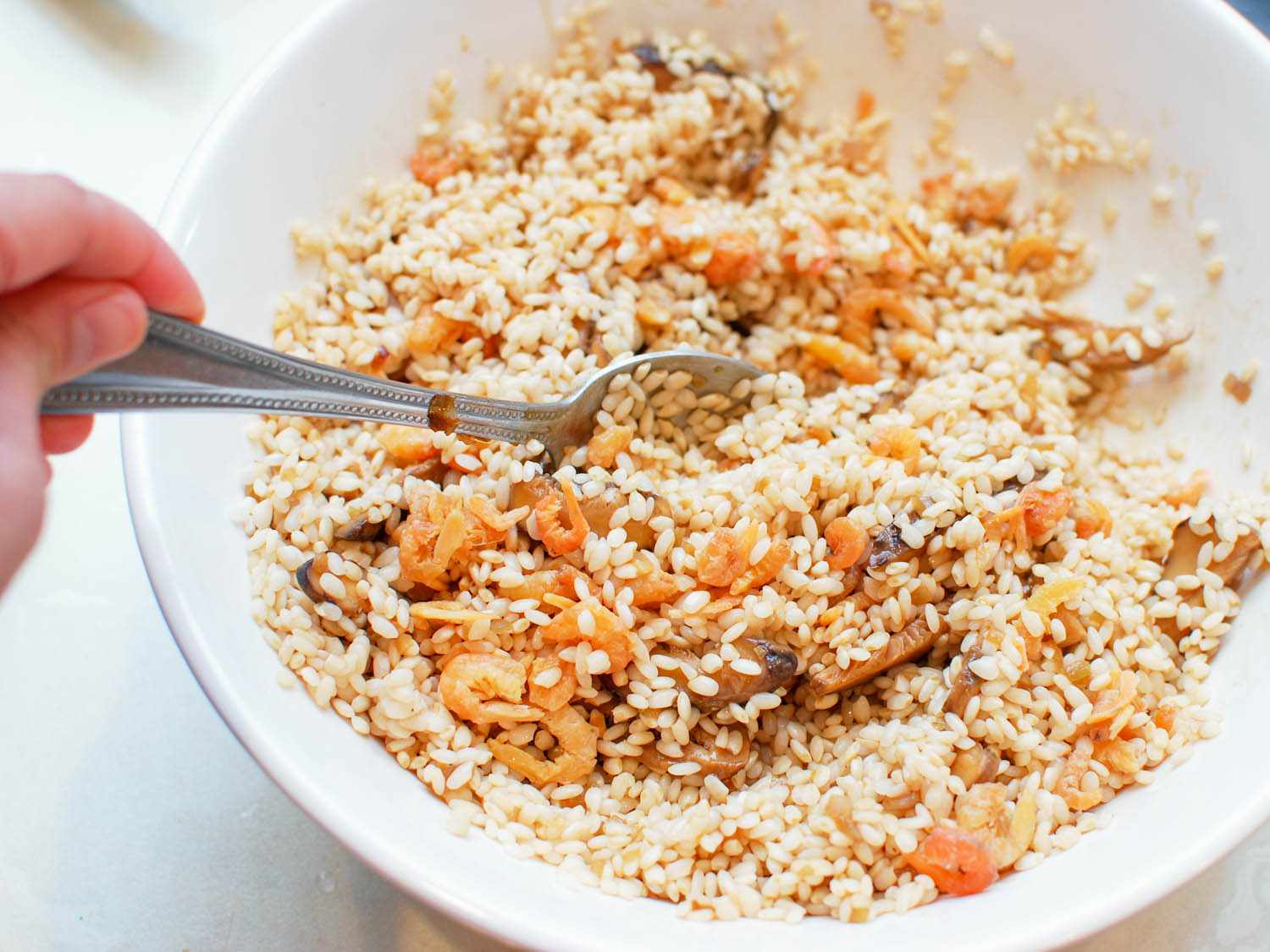 Sticky rice filling being mixed together in a ceramic bowl.