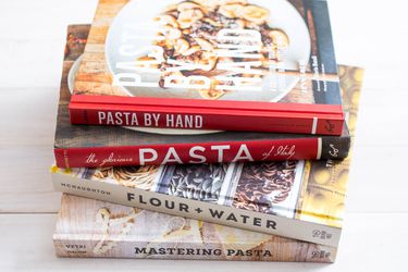 A stack of four cookbooks about pasta. 