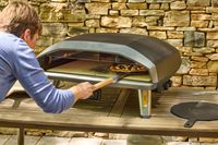 A person cooks a pizza in the Ooni Koda 2 Max Gas Powered Pizza Oven