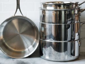 A stack of stainless steel pots and a frying pan resting on a countertop