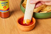 Person dipping tortilla in Louisiana The Perfect Hot Sauce