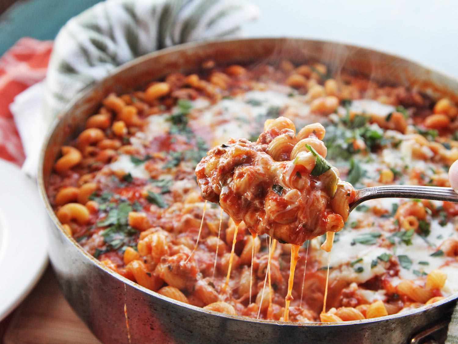 Melted cheese dripping off a serving spoonful of American Chop Suey