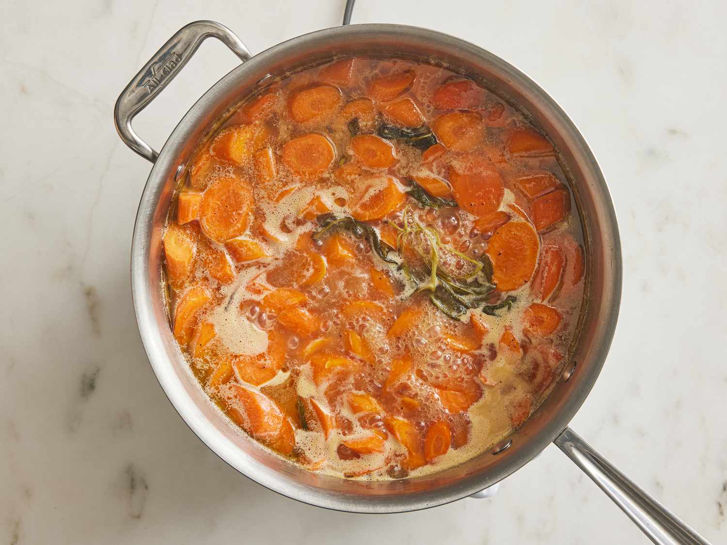 Carrots boiling into pan with butter and sage 