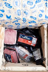 An opened Good Chop box containing various vacuumsealed packages of meat products with visible labels