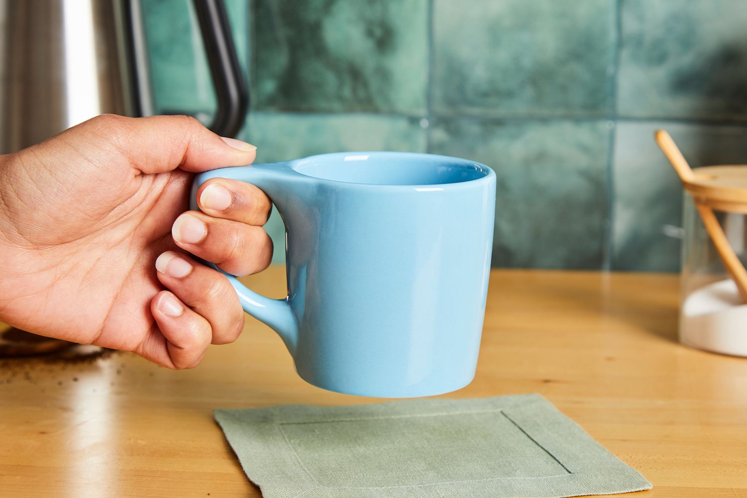 A person picking up a blue coffee mug.