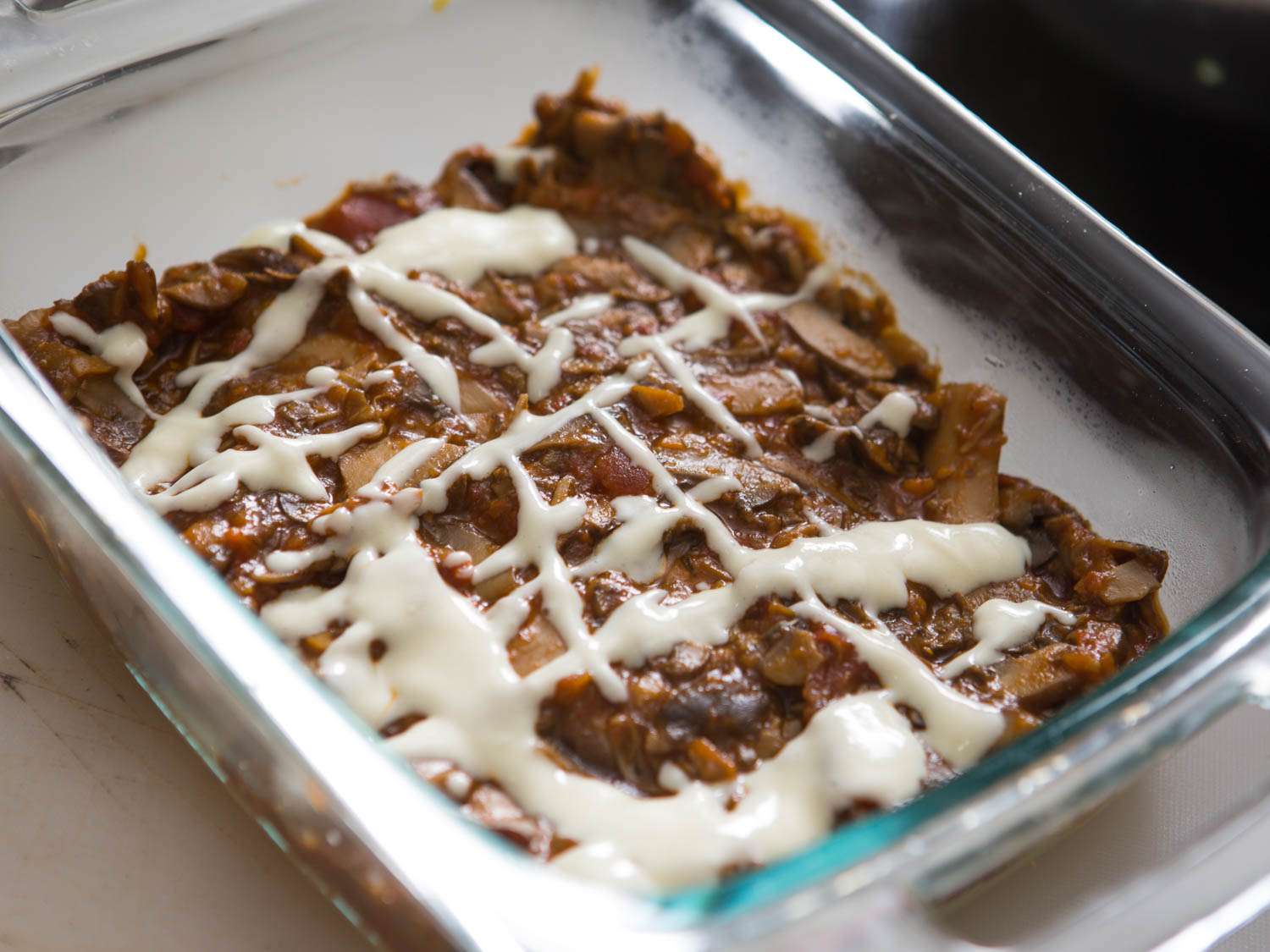 The layer of polenta is covered with mushroom ragù and drizzled all over with Parmesan cream.