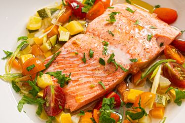 Cooked salmon filet served with diced vegetables and herbs