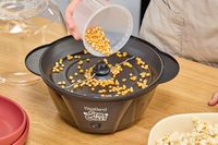 A person pours popcorn kernels into the West Bend Stir Crazy Electric Hot Oil Popcorn Popper