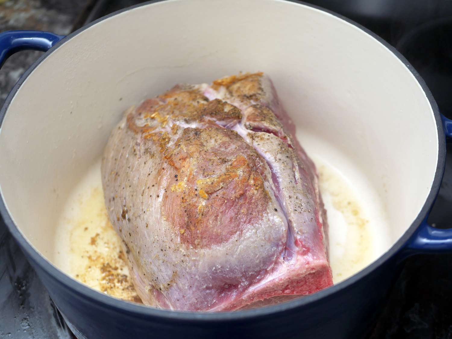 a close up of the pork shoulder searing in the tramontina dutch oven