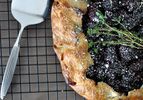 Overhead closeup of a blackberry thyme galette, cooling on a rack.