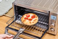 Tonga removing a rack containing pizza from the Breville the Compact Smart Oven