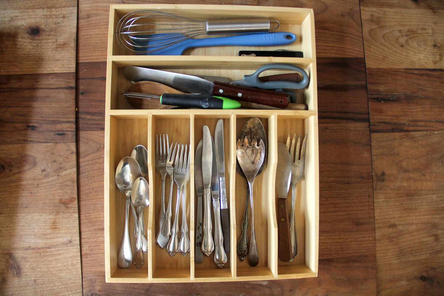 A bamboo kitchen drawer organizer on a wooden surface.
