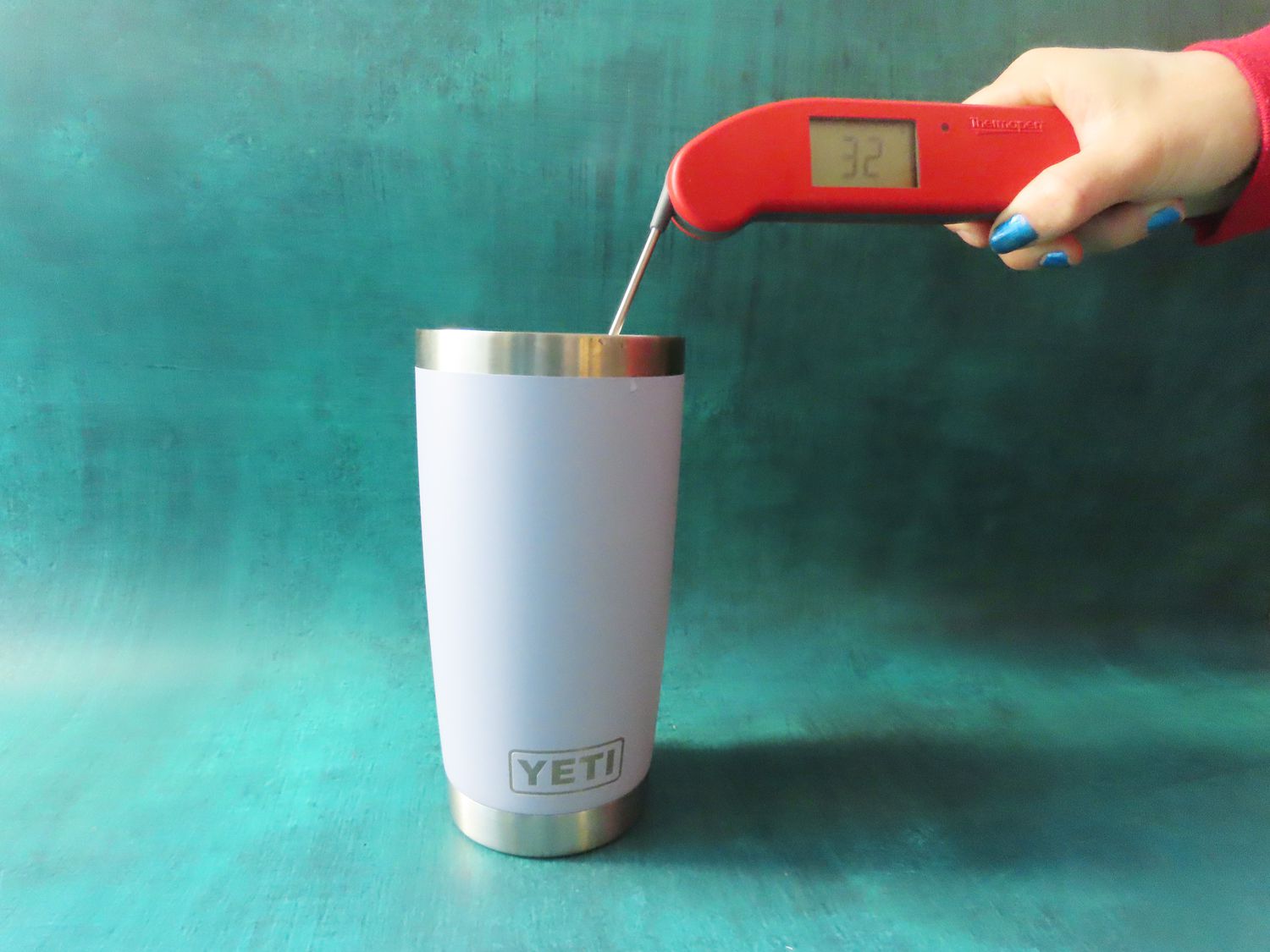 a person taking the temperatre of ice water with an instant-read thermometer