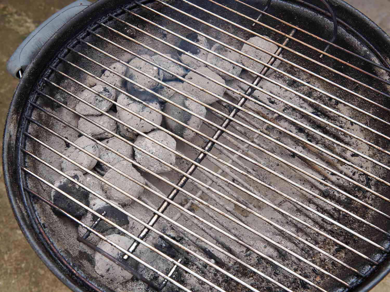 Gray ash covered coals spread evenly over half of coal grate 