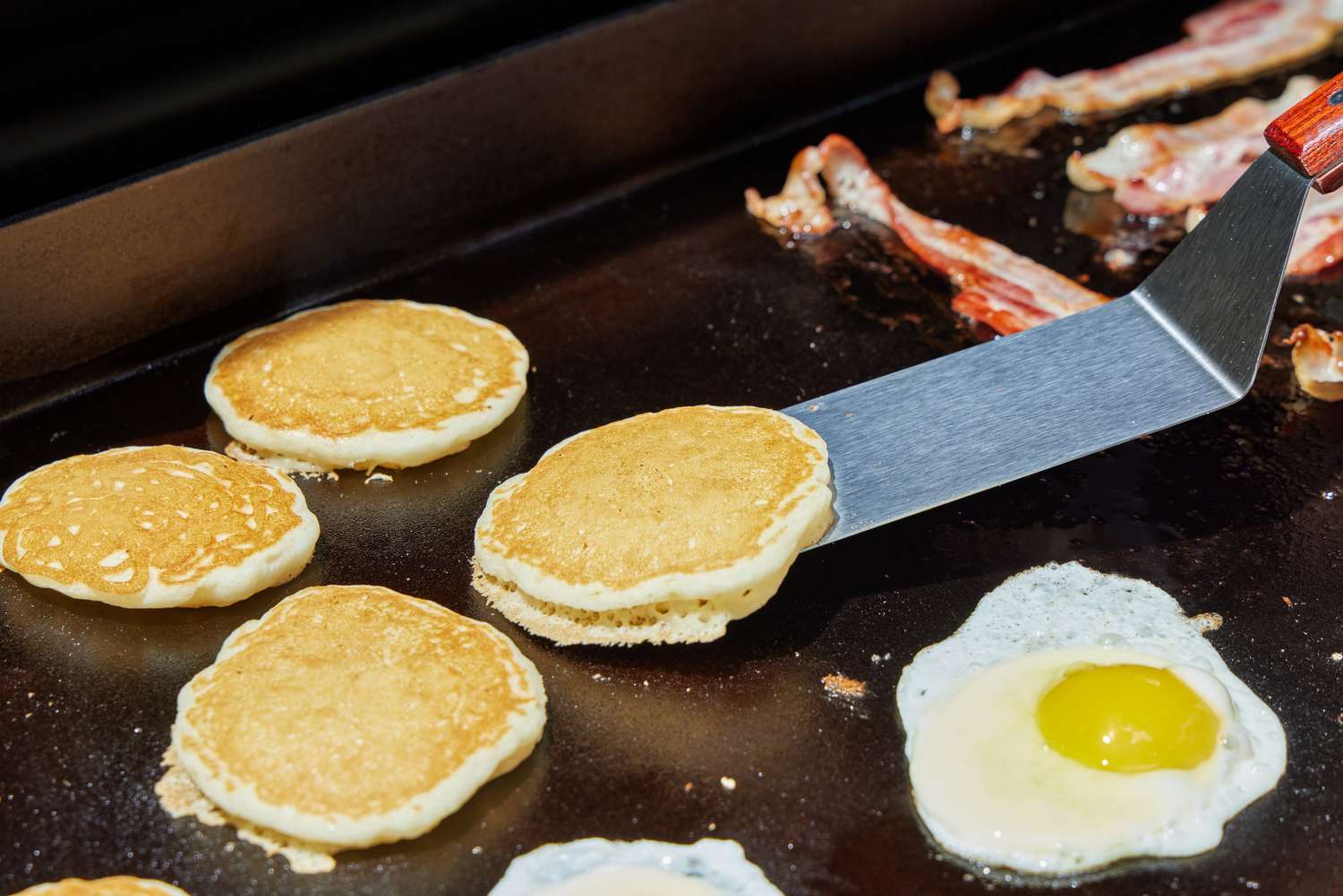 A person cooks pancakes on the Traeger Flatrock Flat Top Grill