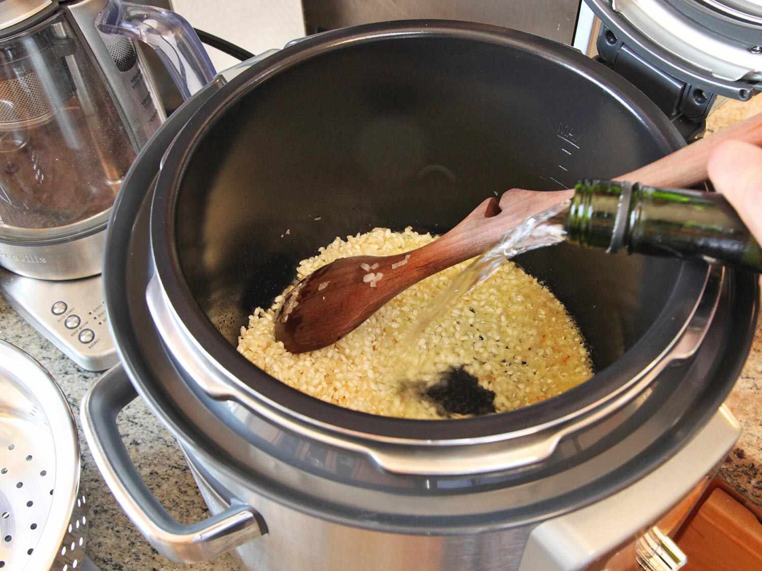 Adding sake to toasted rice in a pressure cooker. 