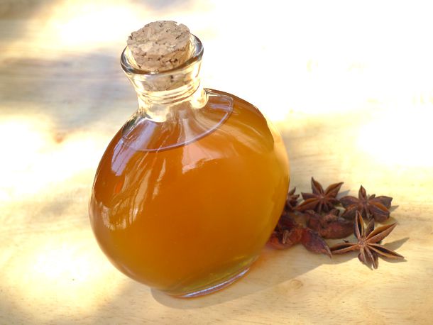 A bottle of homemade pastis next to some star anise pods. 