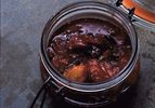 An open glass mason clamp jar filled with plum chutney. 