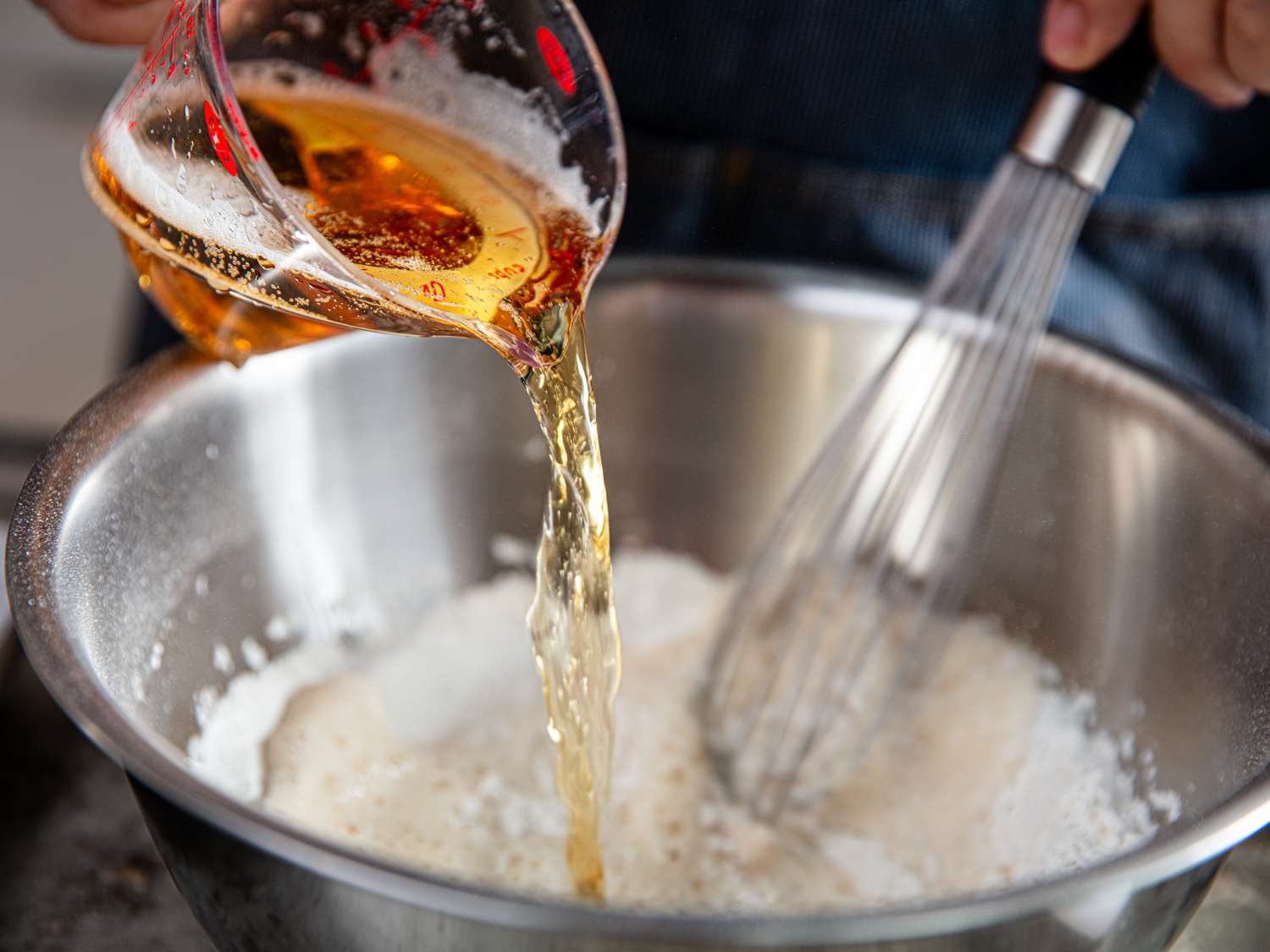 Side view of adding beer to flour for crab batter.