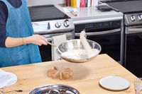 A person flips rice in the All-Clad D3 Stainless-Steel 12-Inch Fry Pan
