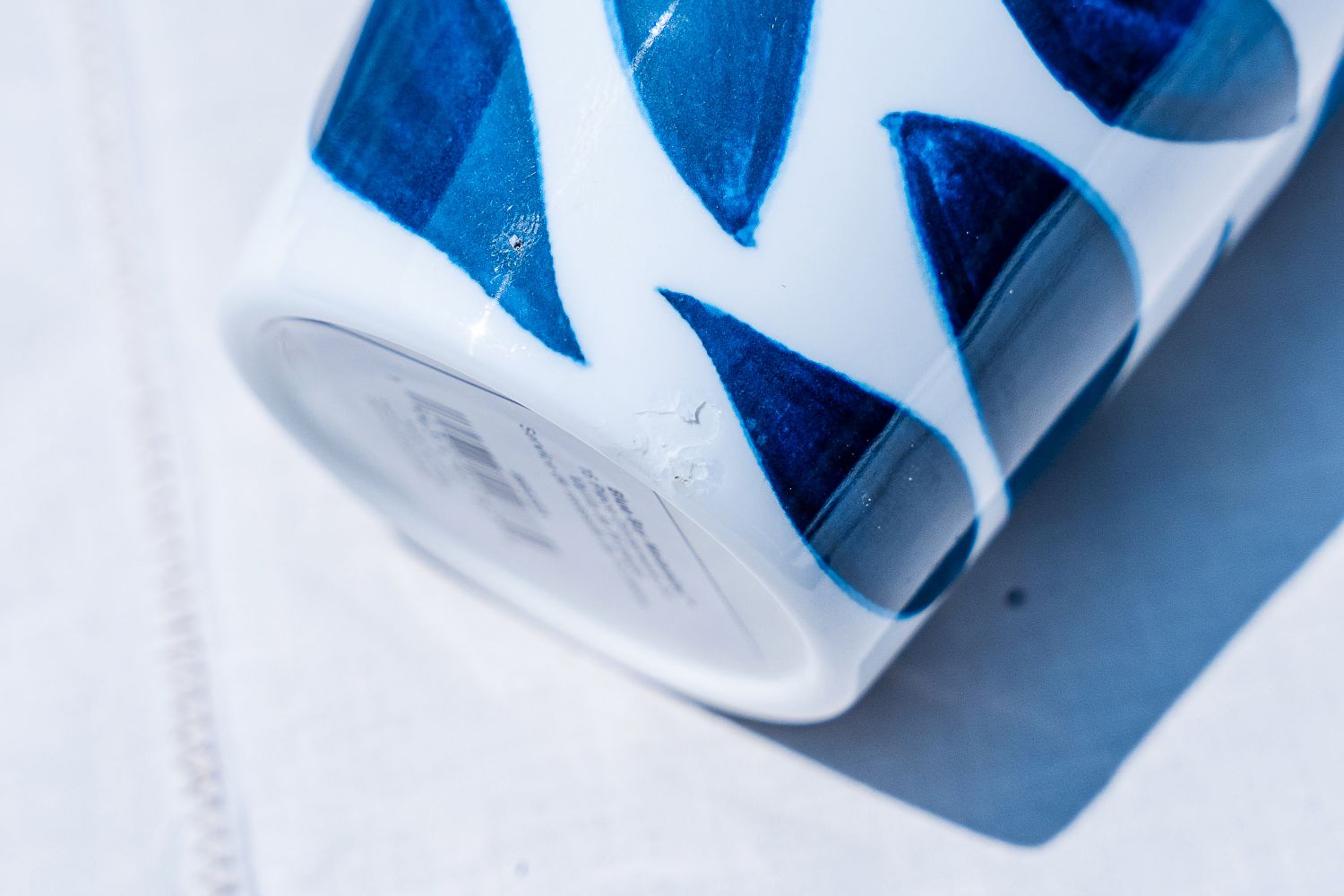 A closeup of a Lenox Blue Bay Melamine Dinnerware Set ceramic cup with blue triangular patterns resting on a light surface