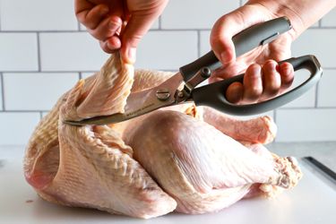 Hands using Williams Sonoma poultry shears to cut a turkey wing