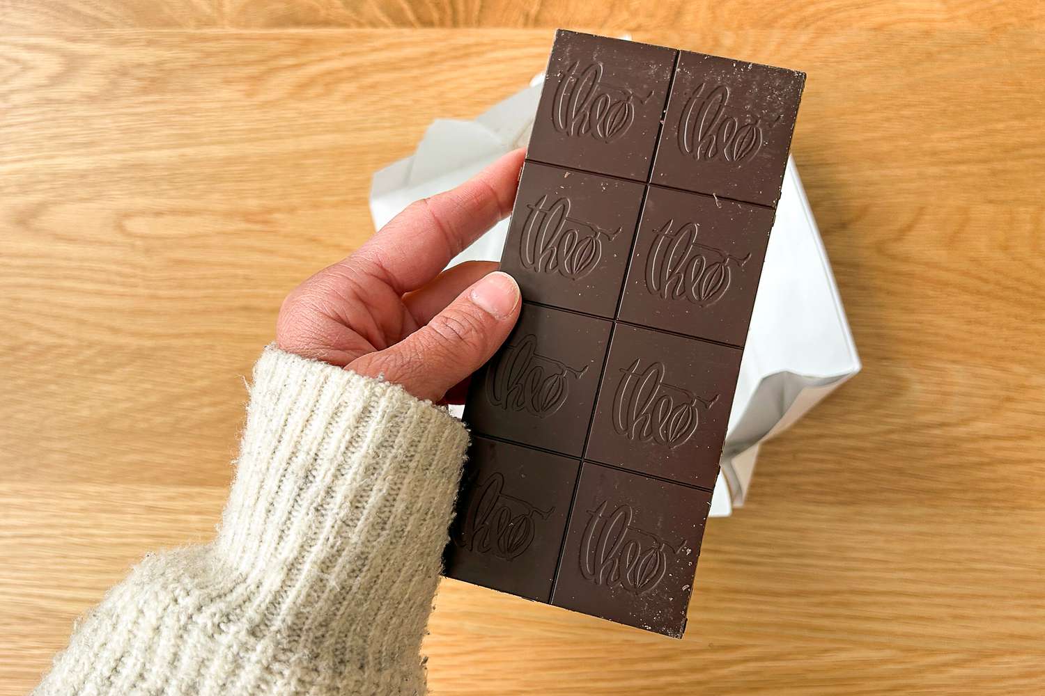 A person holding the Theo Pure Dark 85% Chocolate Bar unwrapped
