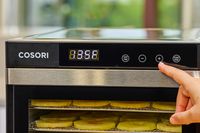 A person pressing a button of COSORI Food Dehydrator