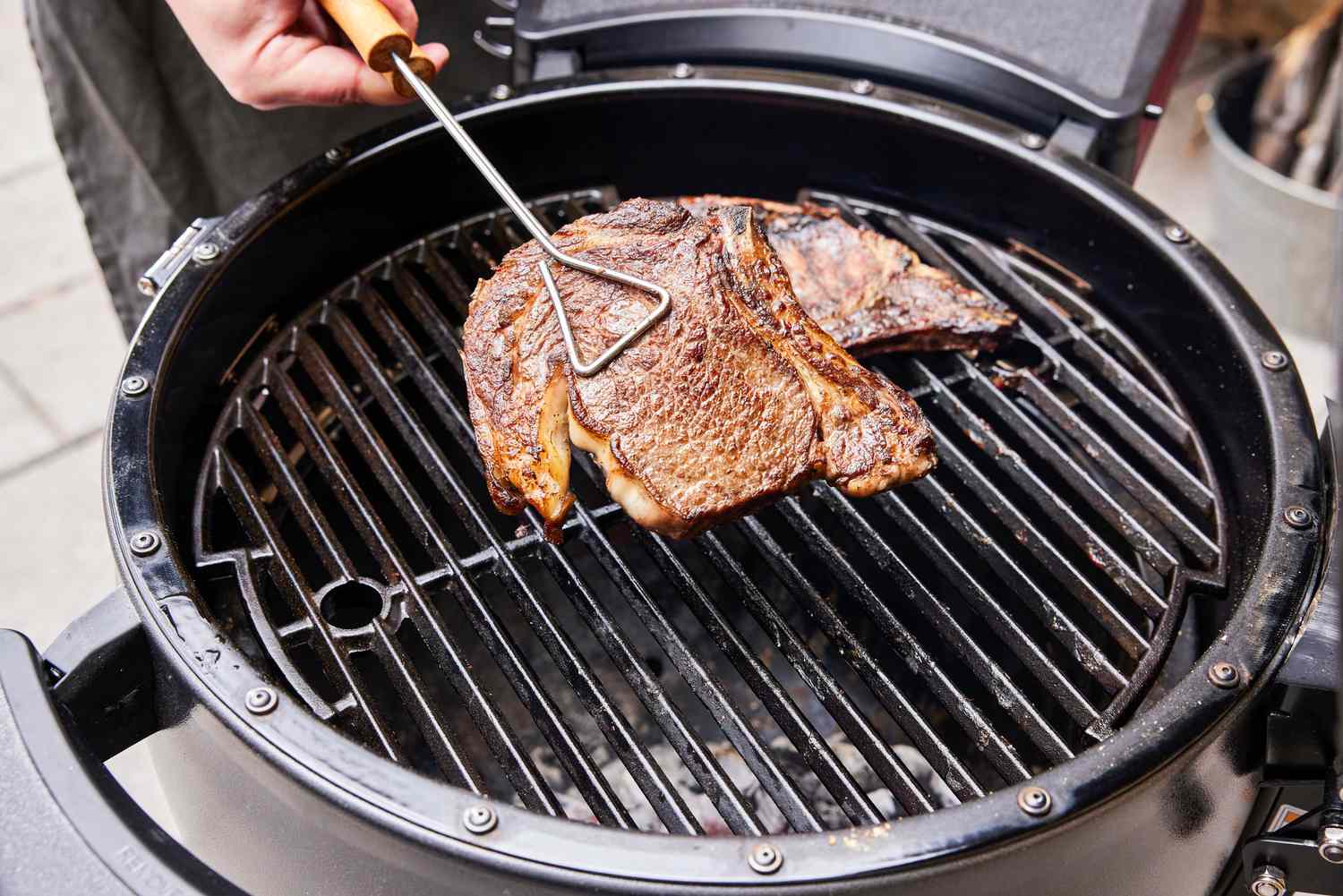 A person cooks meat in the Broil King Keg Kamado Charcoal Grill