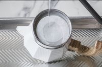 Boiling water being poured into a stovetop coffee maker with a filter