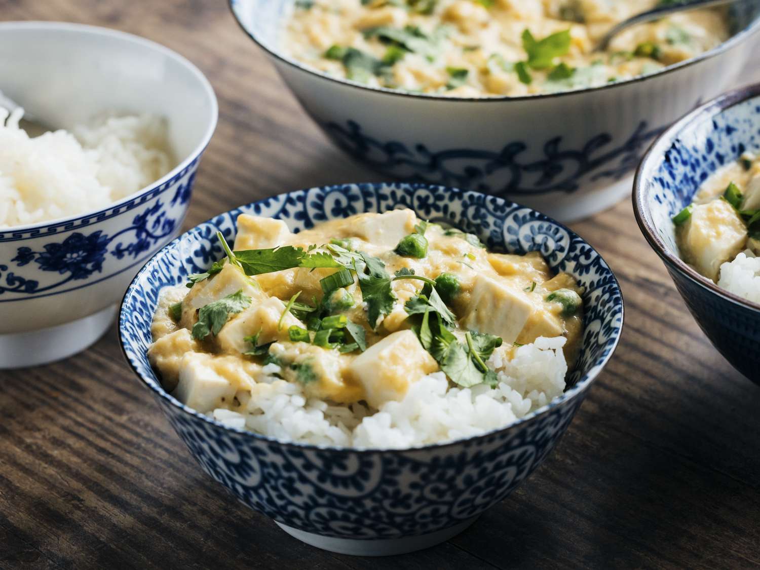 Angled view of 4 blue patterned dishes plated with the finished slippery eggs with tofu and peas.