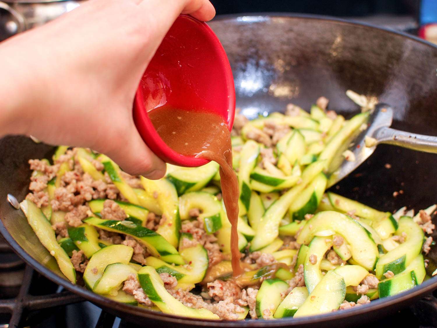 Adding sauce to the cucumber and pork stir-fry. 