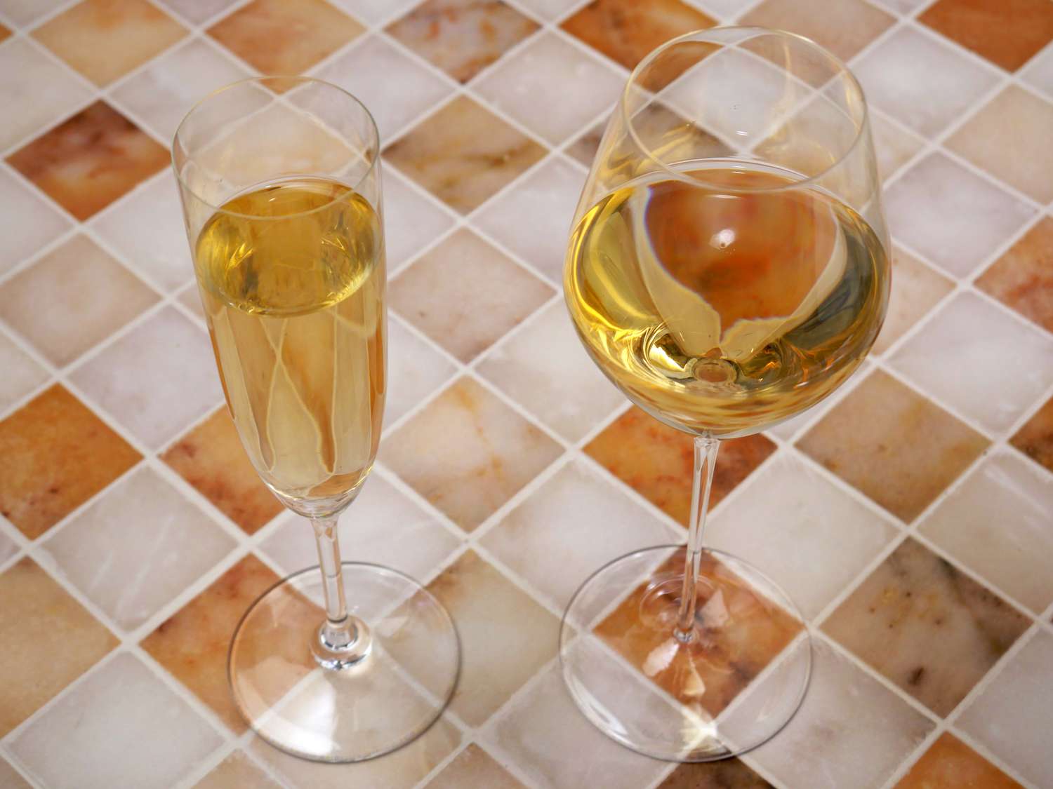a flute glass with champagne next to a tulip-style champagne glass with champagne.