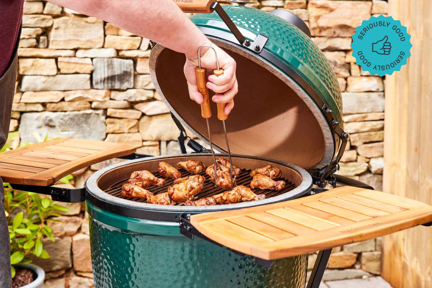 A Big Green Egg kamado smoker loaded with chicken wings.