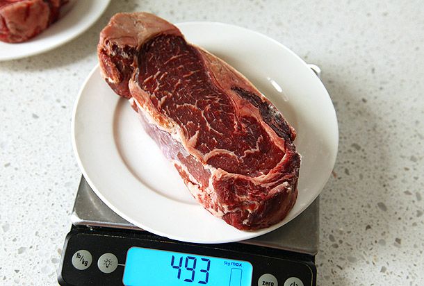 A steak dry-aged at home being weighed on a kitchen scale.